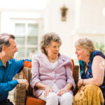 elderly woman sitting on couch with two adults