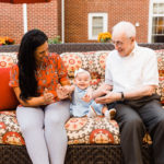 mother of infant, infant, and elderly man sitting on bench