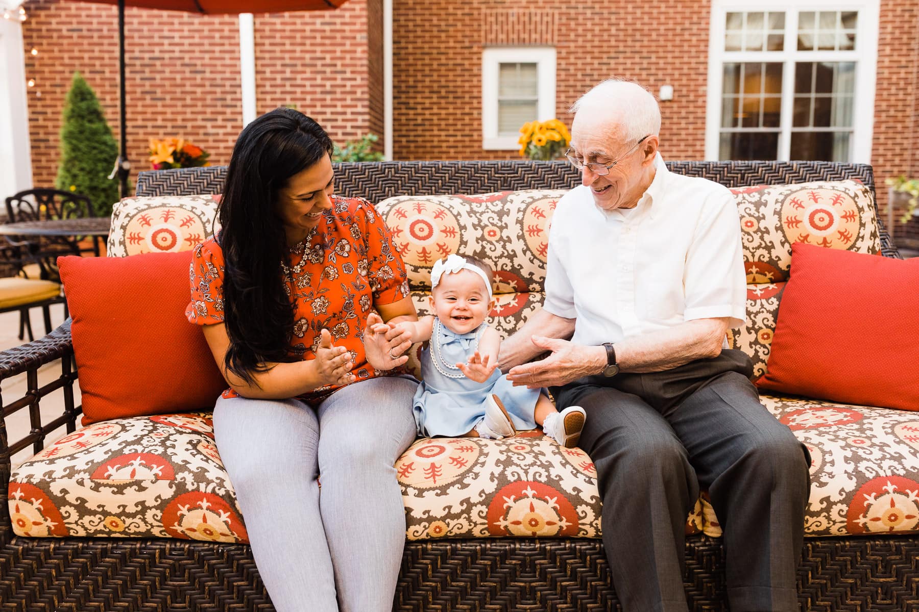 mother of infant, infant, and elderly man sitting on bench