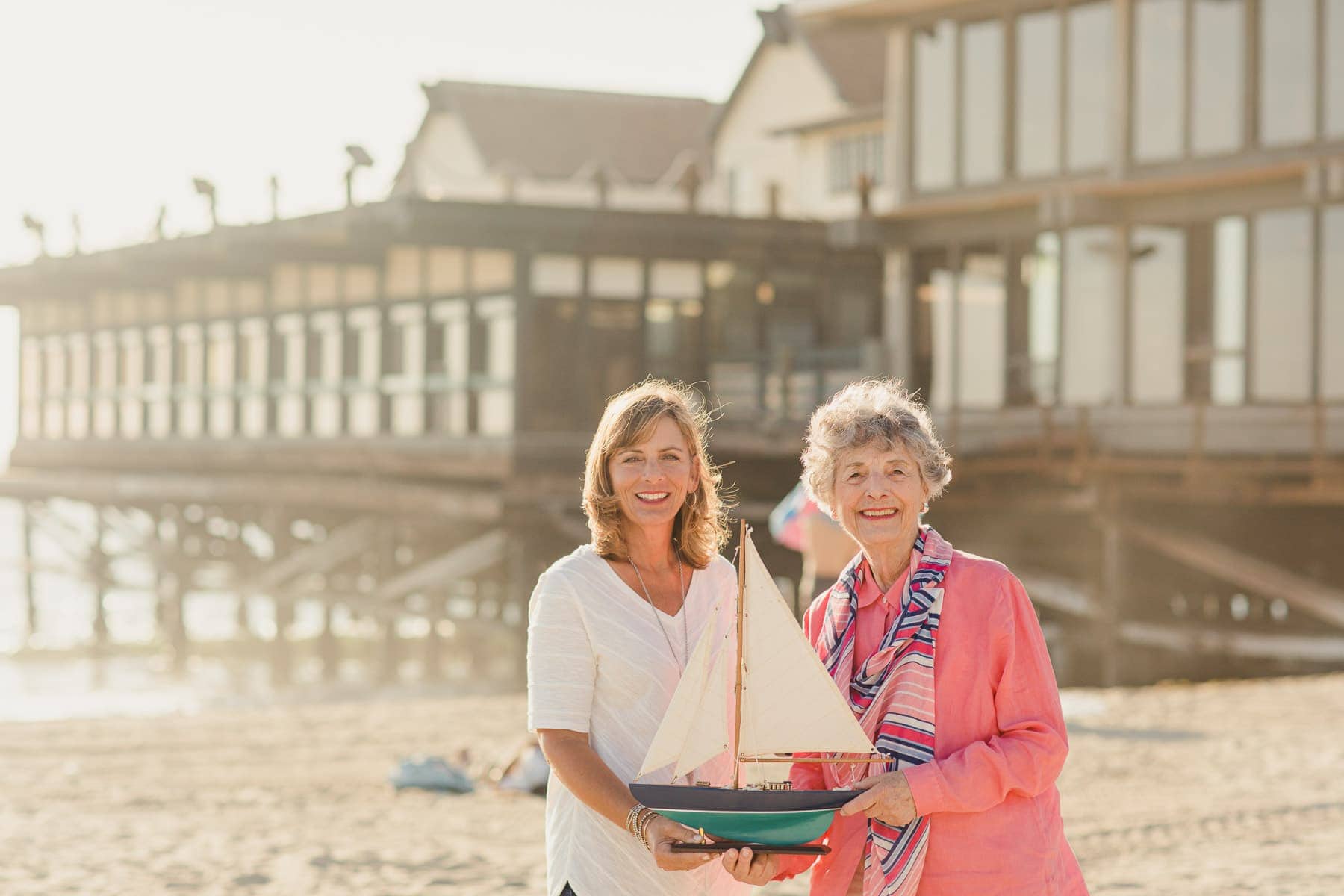 elderly mother and daughter holding sail boat on the beach