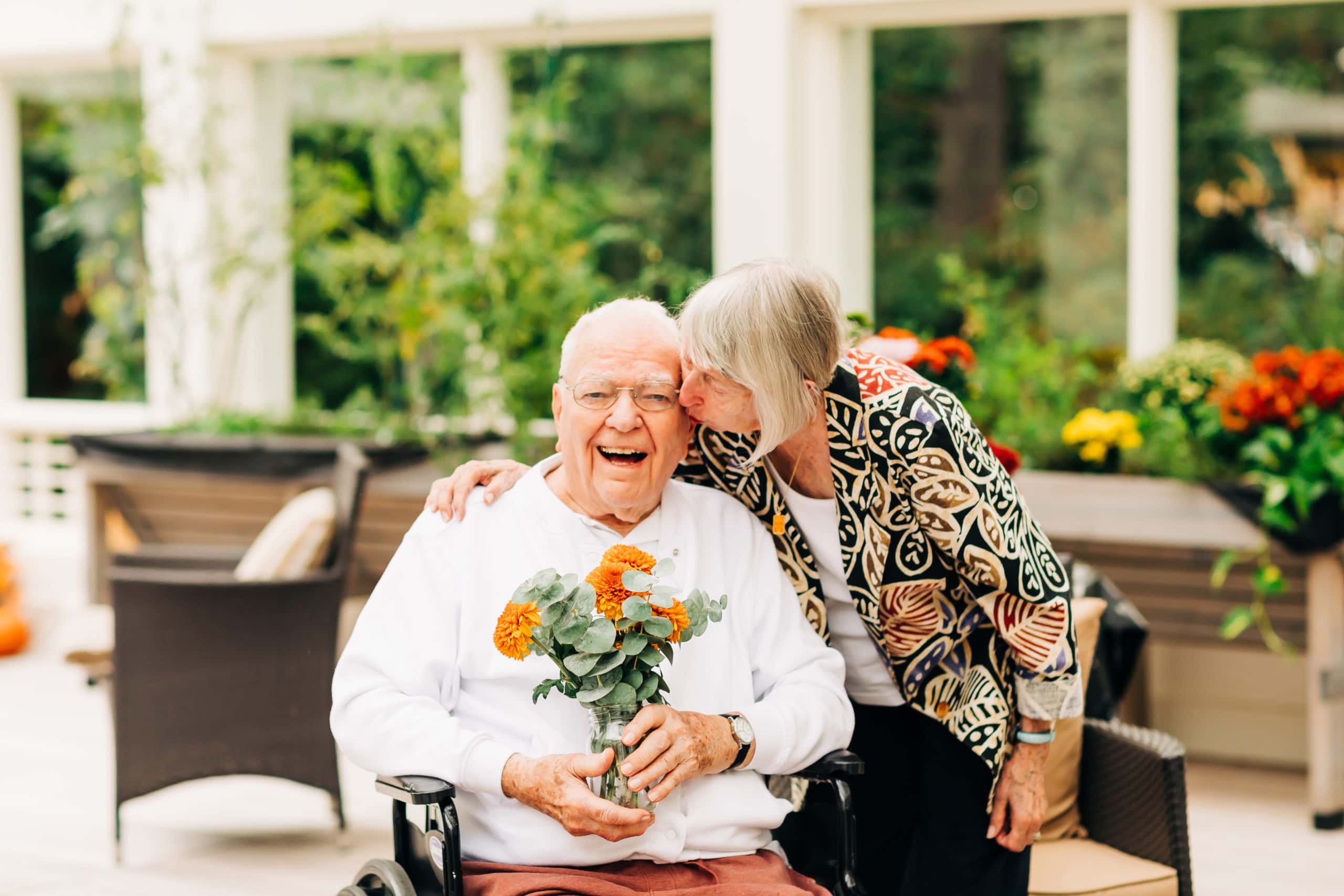 senior couple kissing and holding flowers