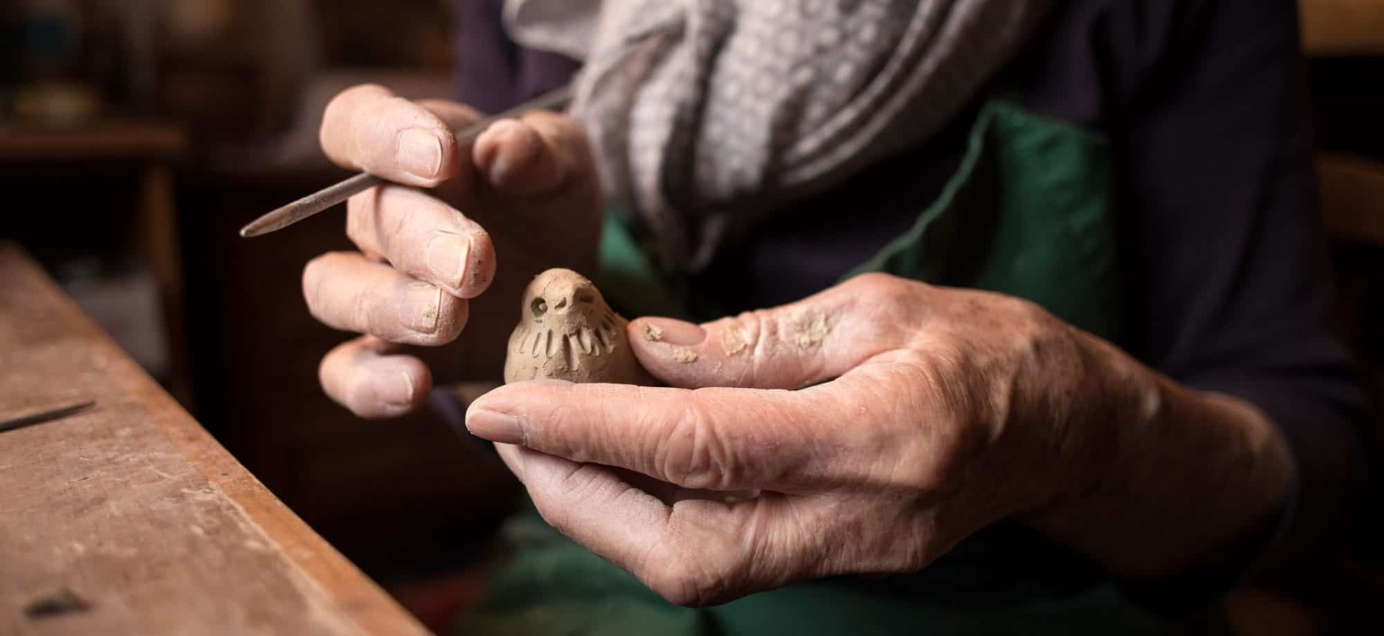 hands holding clay art in the shape of a bird