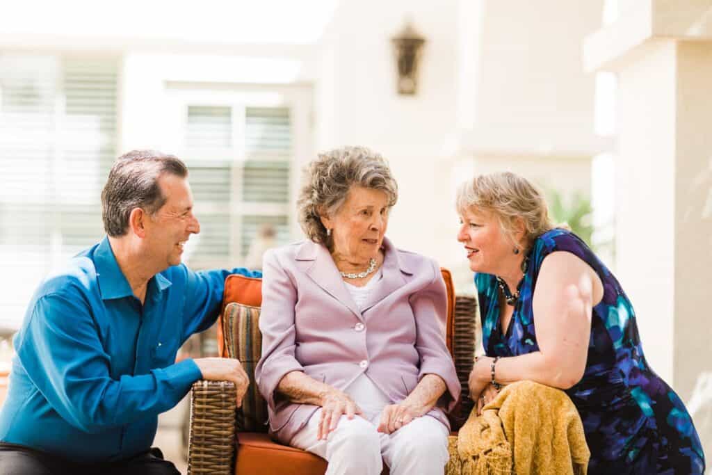 elderly woman sitting on couch with two adults