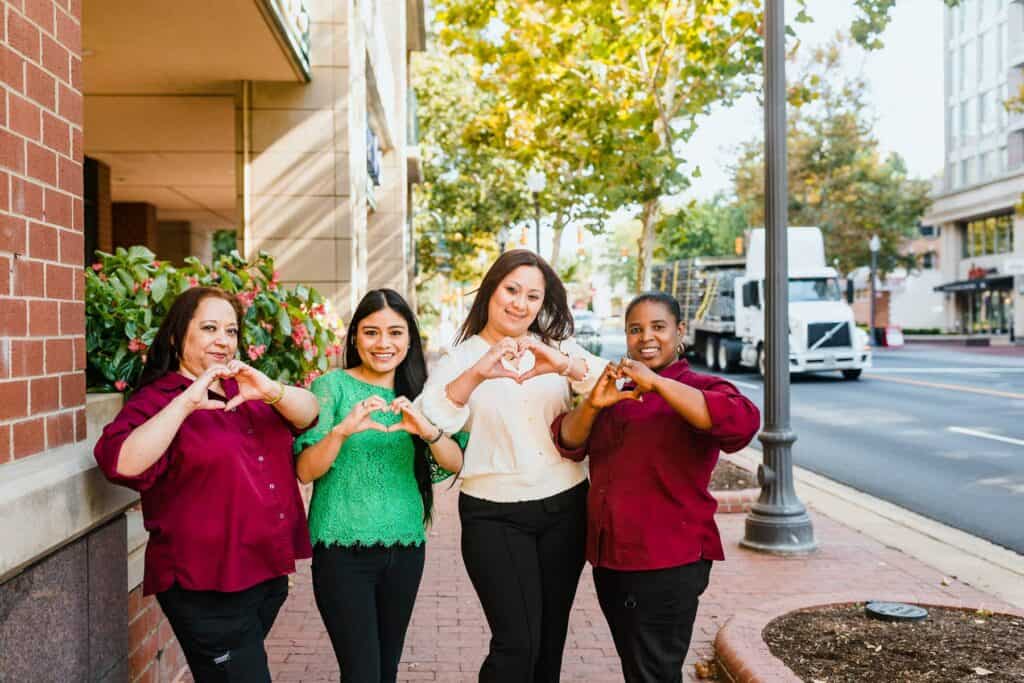 team members making hearts with their hands and smiling