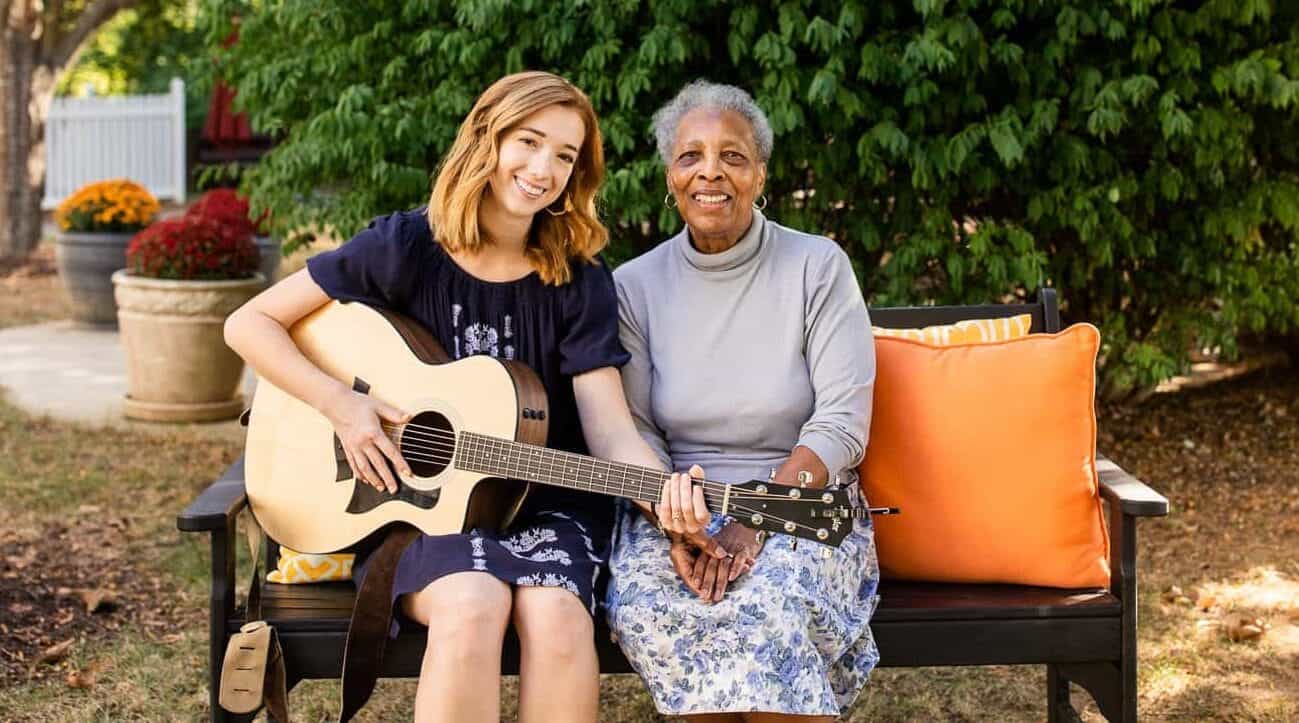 younger woman with guitar sitting with older woman
