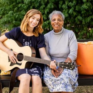 younger woman with guitar sitting with older woman