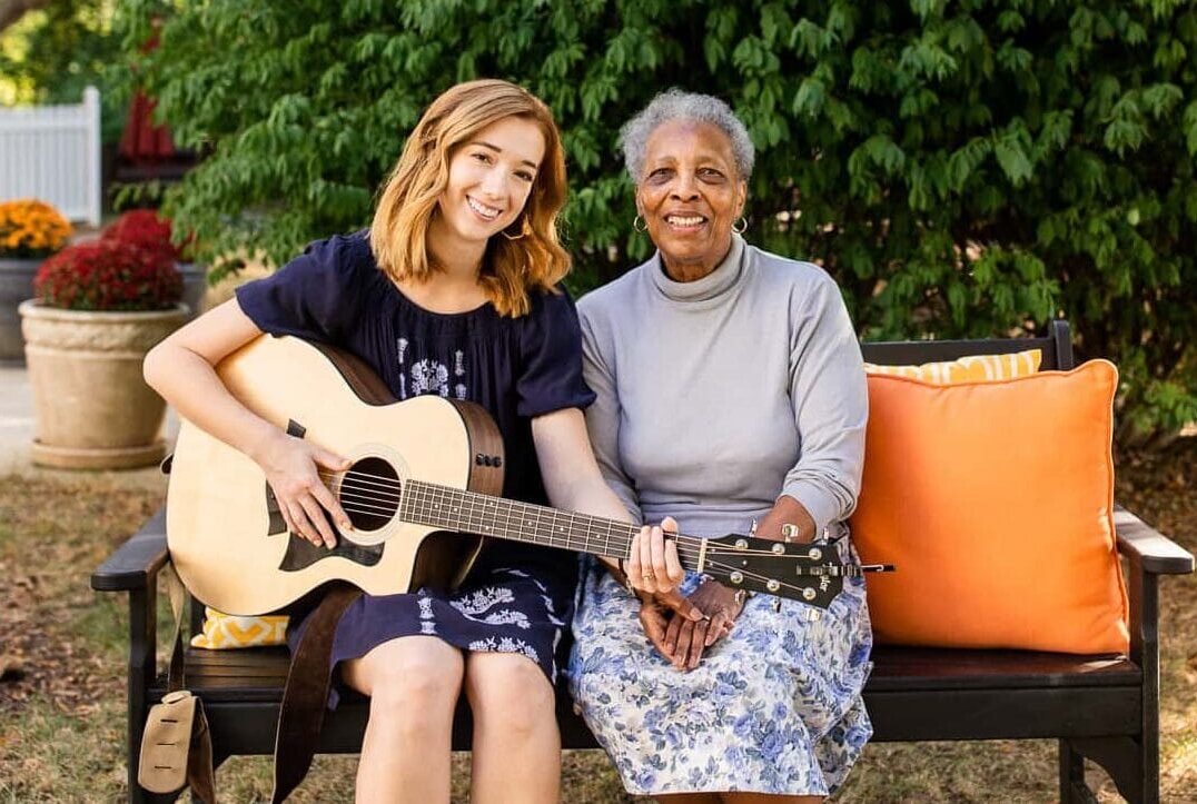 younger woman with guitar sitting with older woman