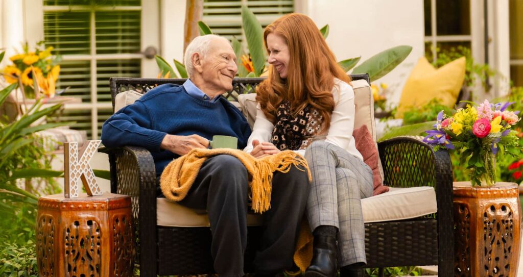 younger woman sitting with older man on bench