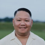 A man in a white shirt standing in a field.
