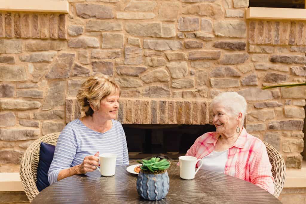 Two women sitting at a table with coffee and tea.