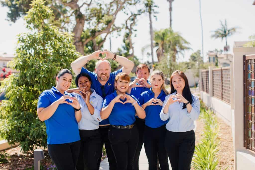 A group of people in blue shirts making a heart shape.