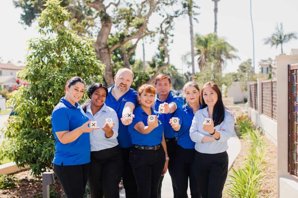 A group of people in blue shirts and ties holding up their hands.