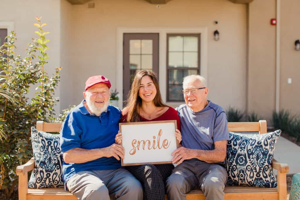 old men with young woman holding sign that says smile